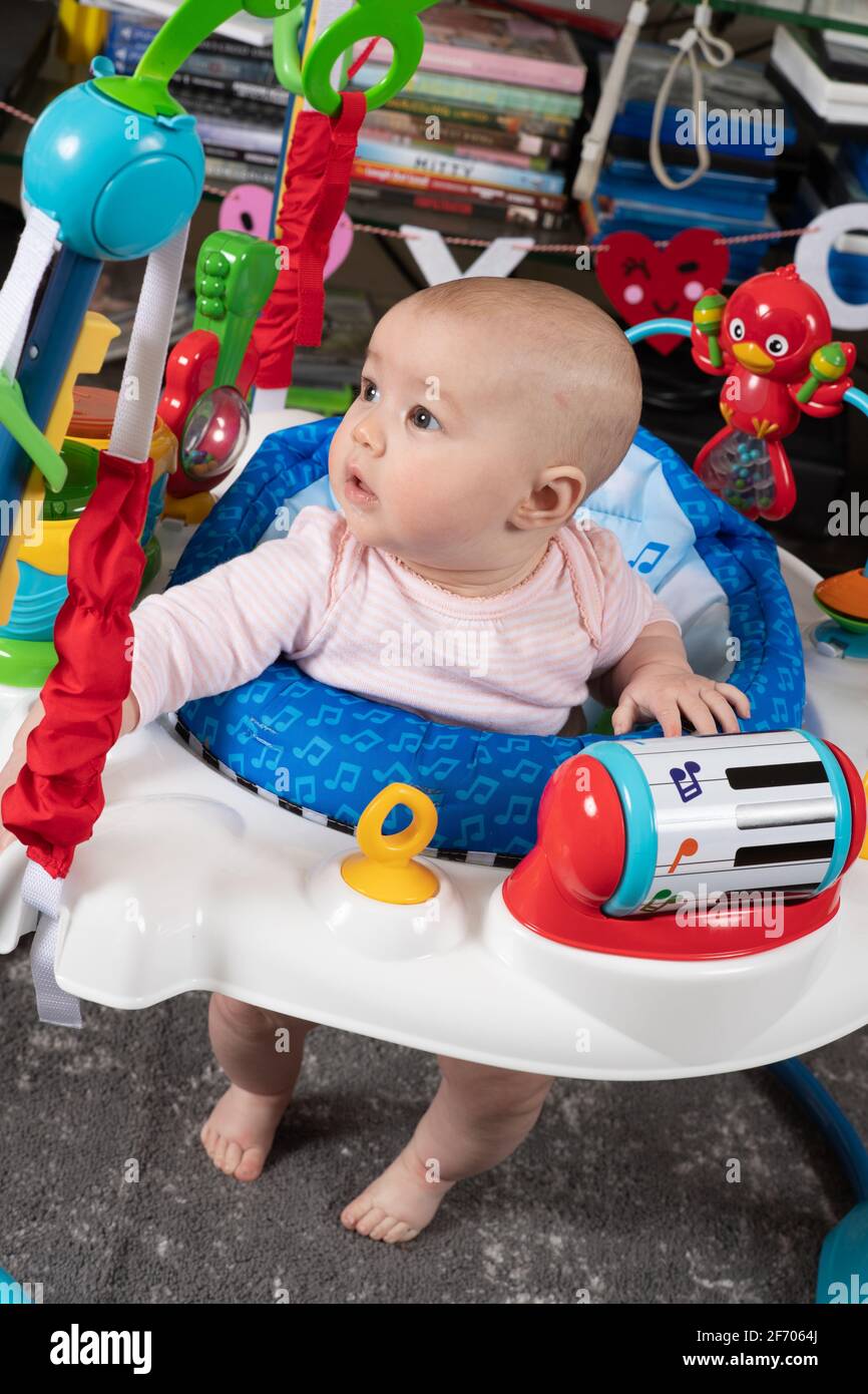 niña de 4 meses en asiento de bebé con juguetes mirando al lado