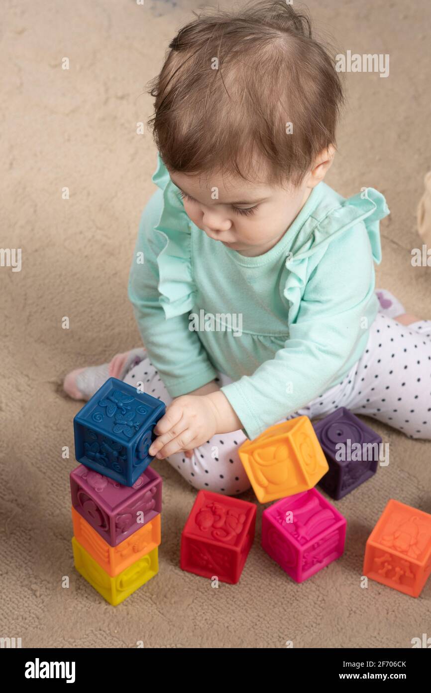 niña de 10 meses poniendo el bloque en de pila de bloques, apilando tres bloques Foto de stock