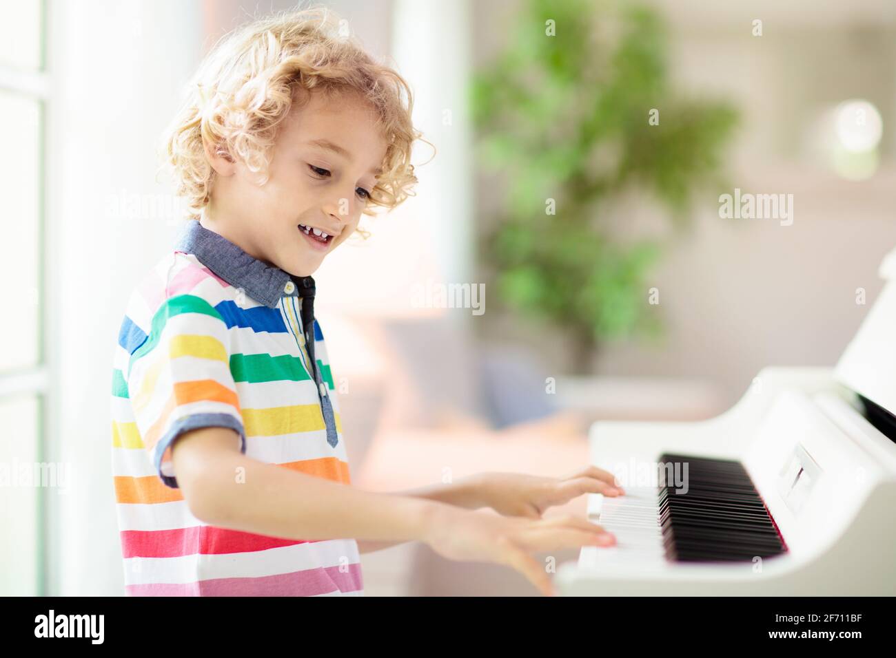 Niño tocando piano. Los niños juegan música. Educación clásica para los  niños. Lección de arte. Un pequeño chico con teclado digital blanco  Fotografía de stock - Alamy