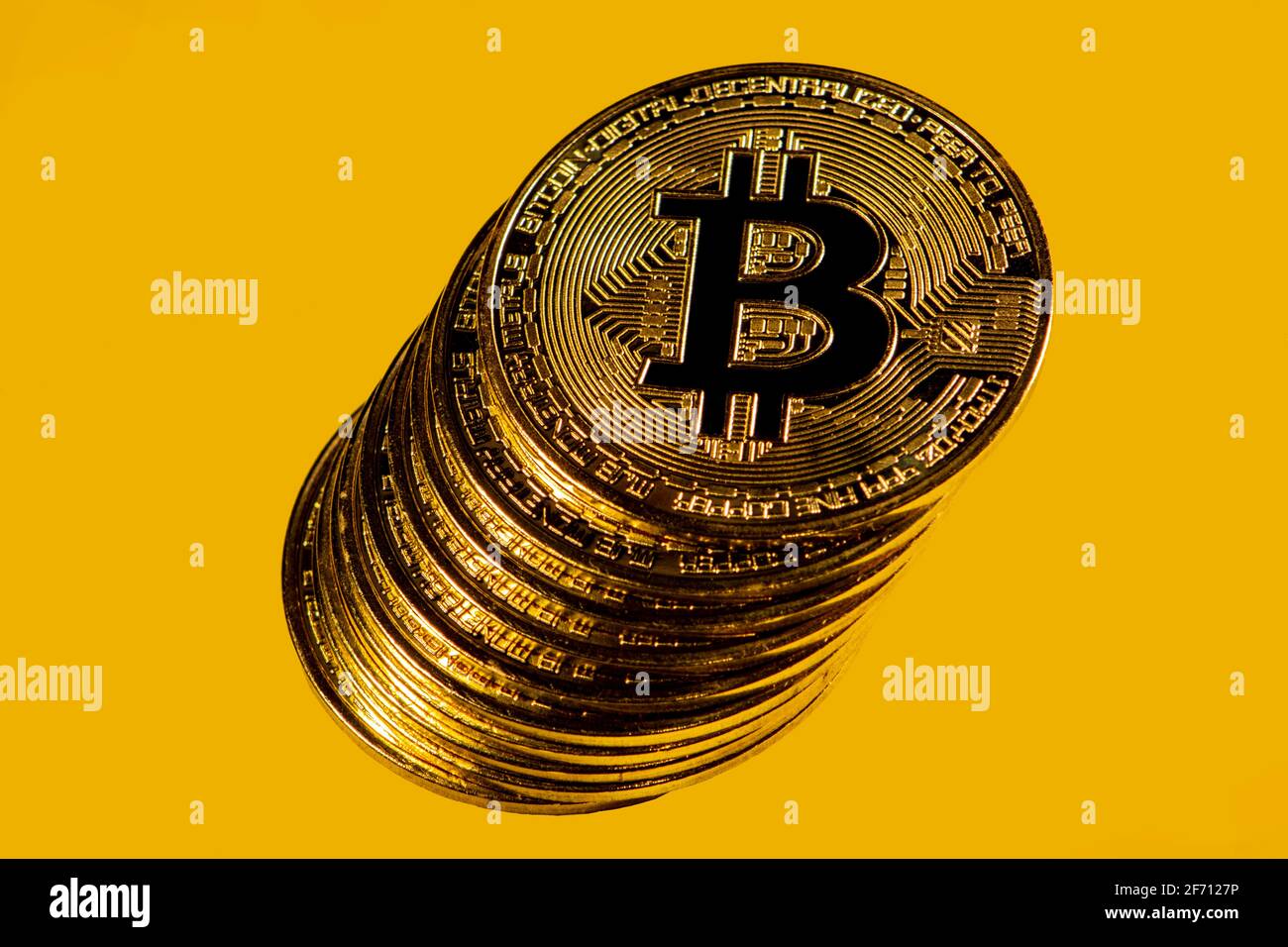 Primer plano de monedas de bitcoin de oro sobre fondo amarillo. Foto de stock