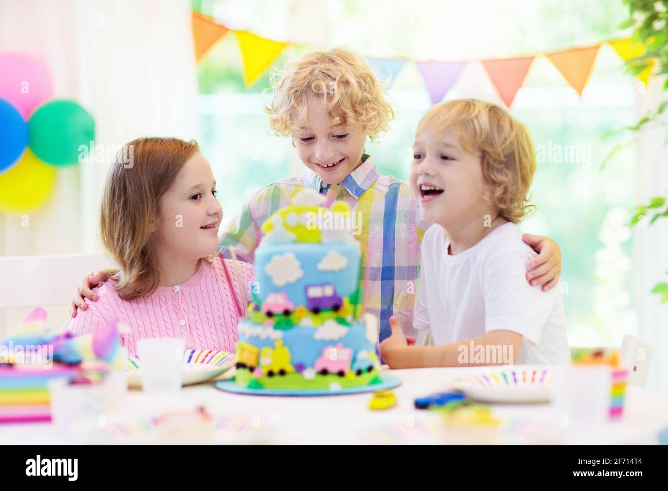 Fiesta De Cumpleanos De Los Ninos Chico Pastel Con Coche Y Avion Nino Soplando Velas En Pastel De Colores Decoracion De Fiestas Banderas Arcoiris Globos Fotografia De Stock Alamy