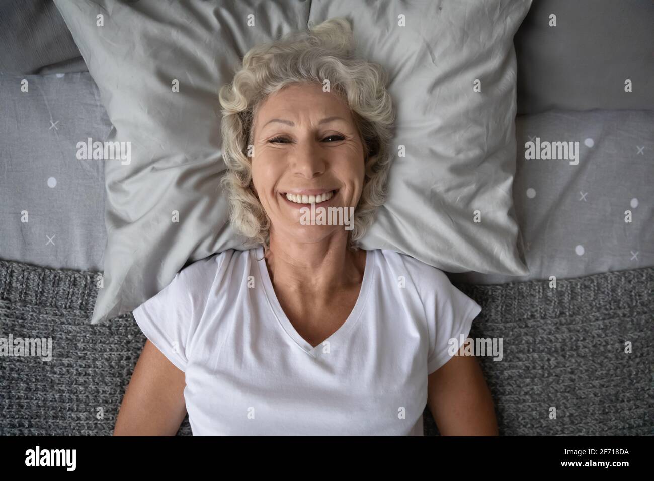 Vista superior retrato de una señora anciana feliz descansando en la cama Foto de stock