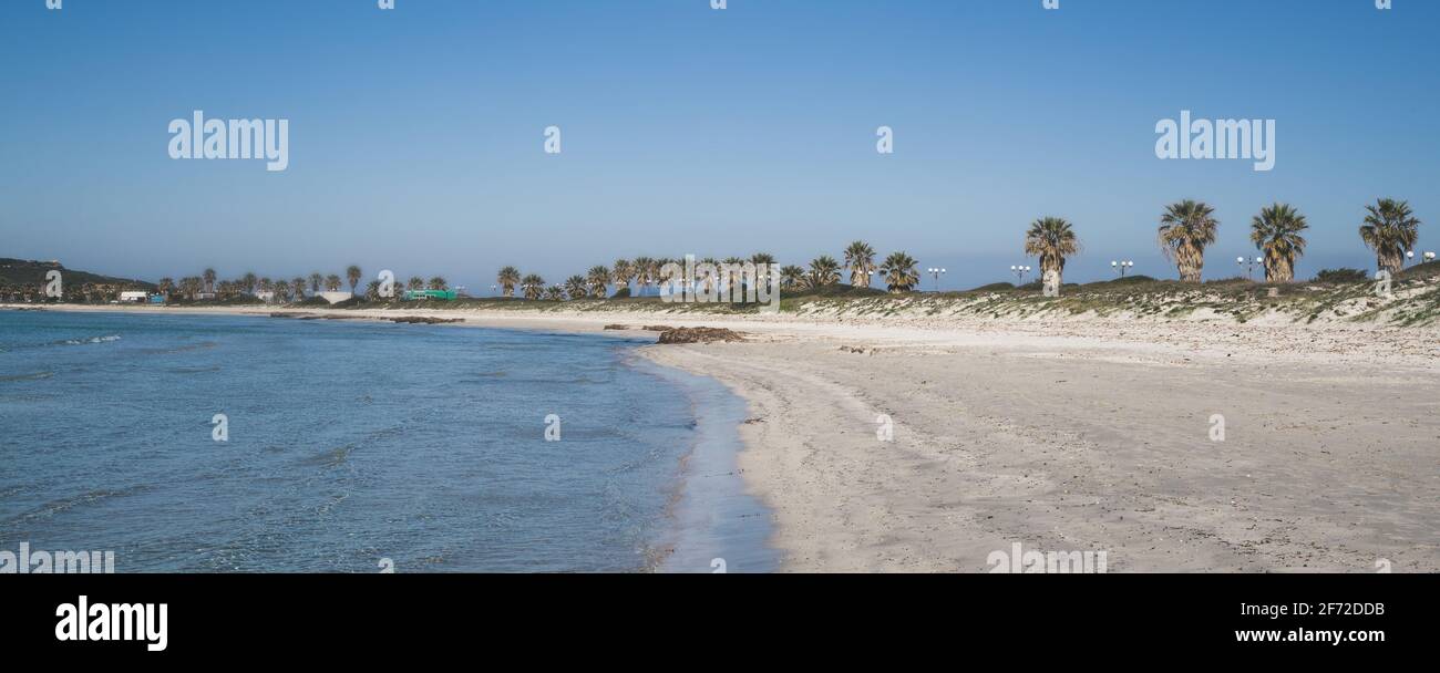 Paisaje de una playa italiana en Cerdeña. Cielo azul, arena blanca y agua clara sin gente. Vista natural de la costa del mar durante el encierro del verano Foto de stock