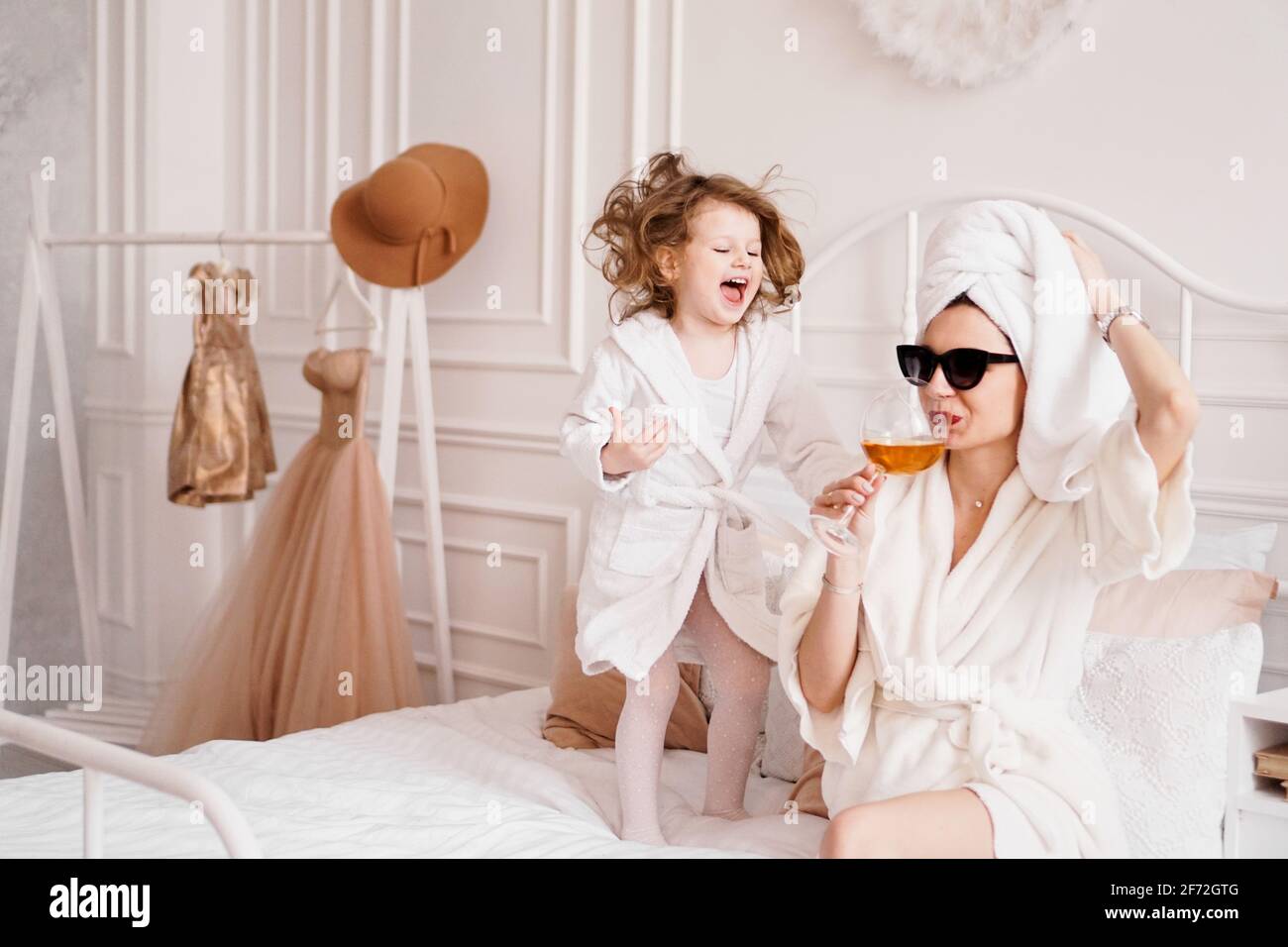 Madre e hija en el dormitorio en batas. Feliz hija está saltando Fotografía  de stock - Alamy