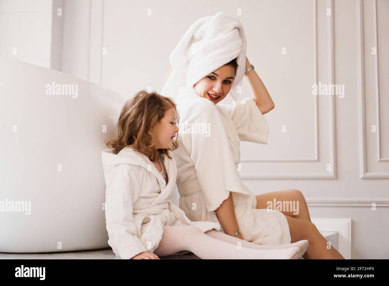Madre e hija en abrigos blancos en el baño Fotografía de stock - Alamy