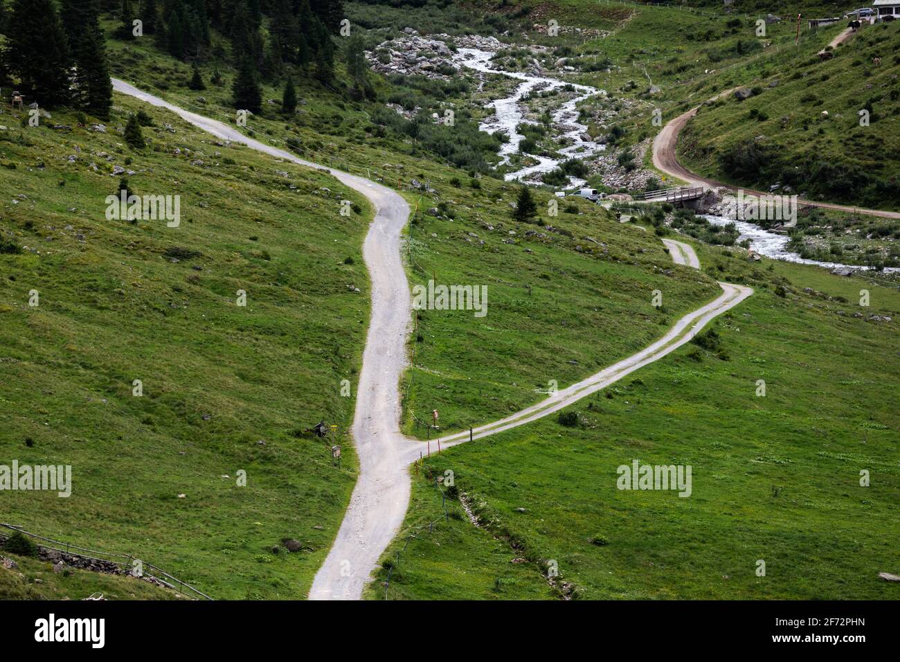 Carretera dividida en dos cerca del río Moosbach a lo largo de la zona de senderismo Alpenrosenweg en Saint Anton am Arlberg, Austria Foto de stock
