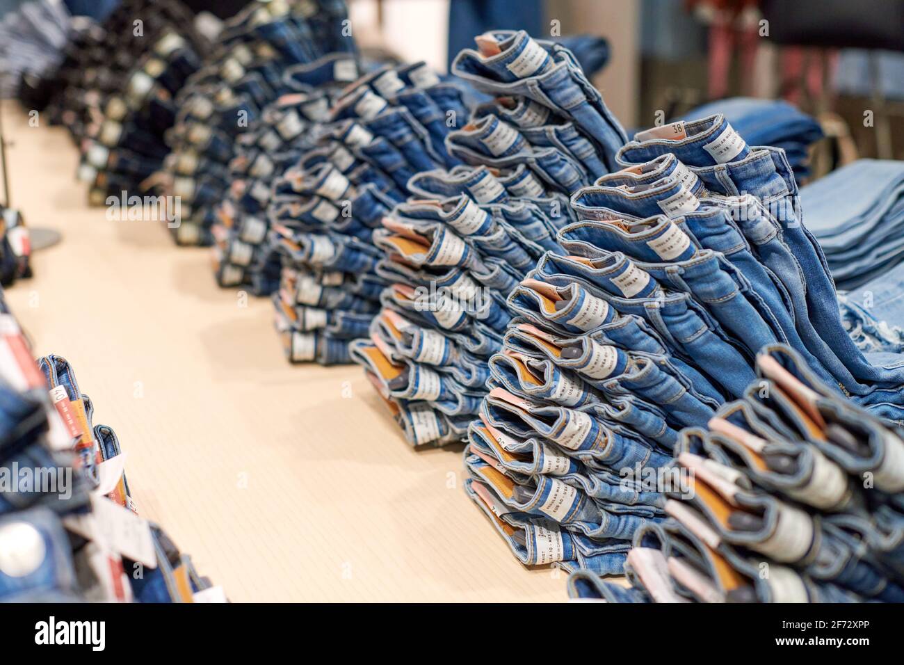 Los vaqueros azules se apilan sobre una mesa de madera en la parte superior  de la tienda de ropa en el moderno centro comercial. Jeans de algodón  doblados en la ventana de