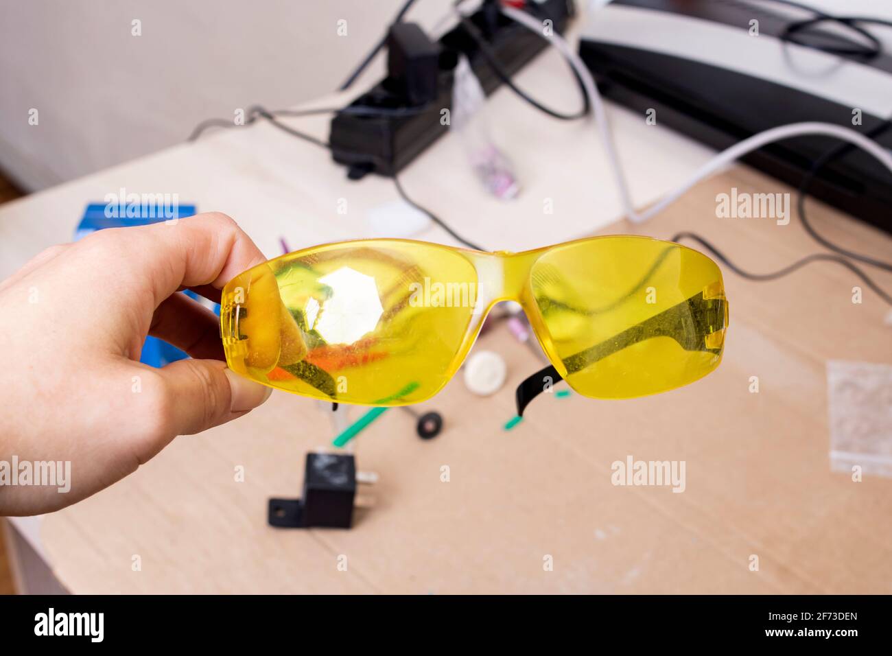 Gafas de protección amarillas en la mano en el escritorio de cerca  Fotografía de stock - Alamy