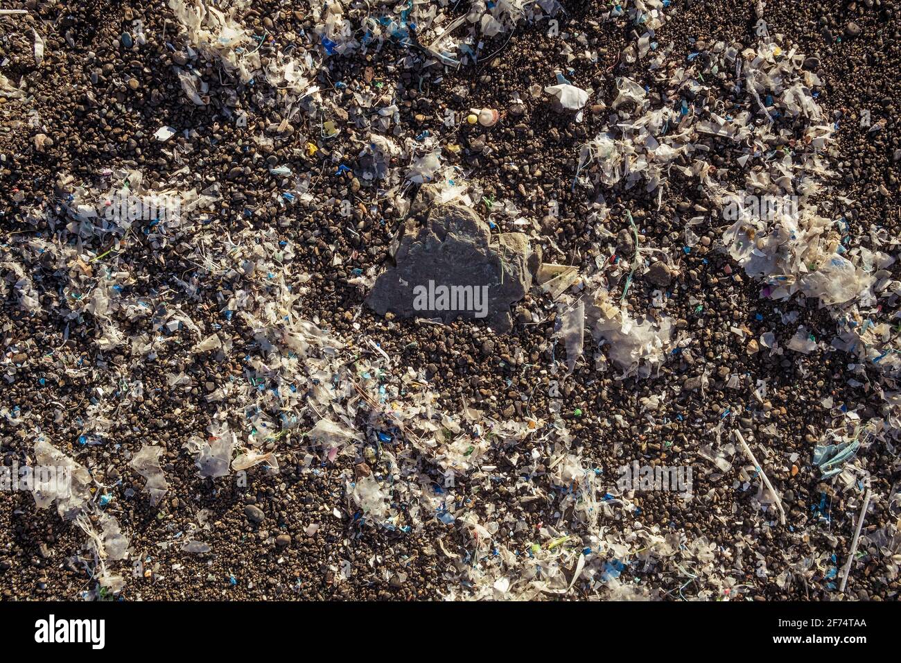Pequeñas piezas de plástico y microplásticos en la playa de arena Foto de stock