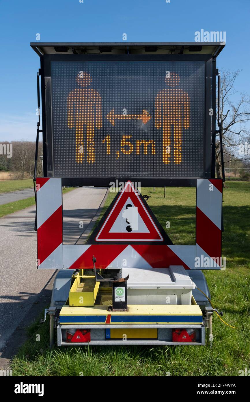 Mantenga una distancia de 1,5 metros señal de advertencia en la pantalla digital en un parque público, recordando a la gente de distanciamiento social para evitar el coronavirus s Foto de stock