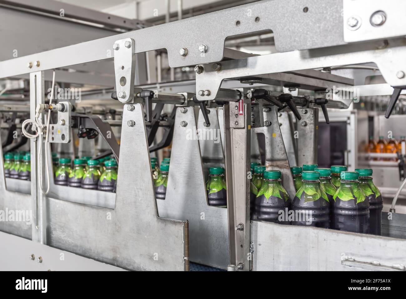 Botellas de plástico con jugo en la fábrica de bebidas moderna línea o banda transportadora automatizada. Foto de stock