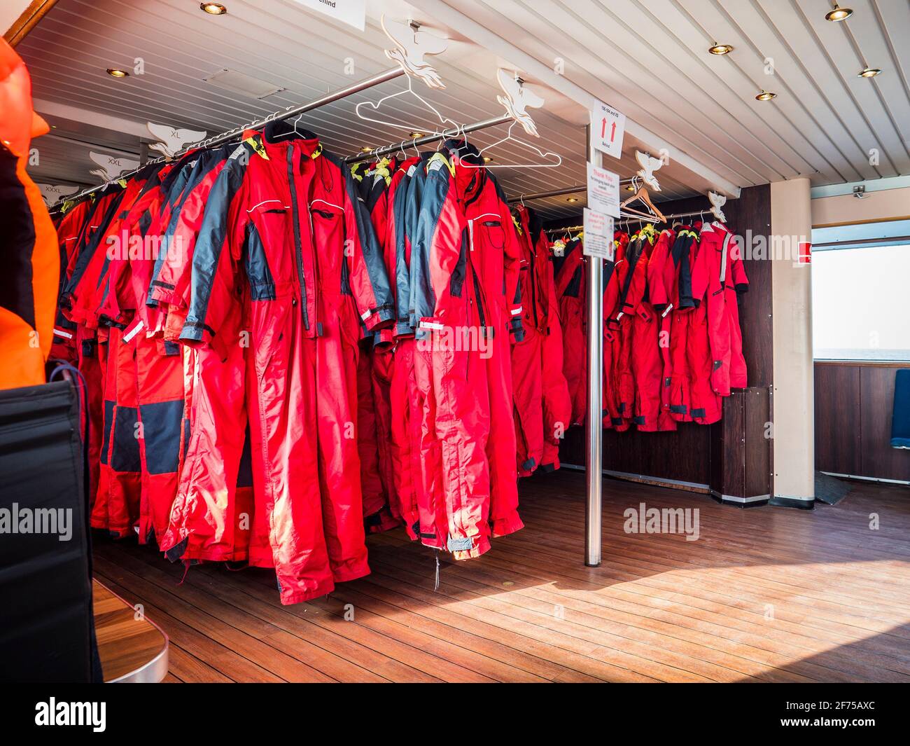 Fila de trajes de supervivencia rojos en perchas Foto de stock