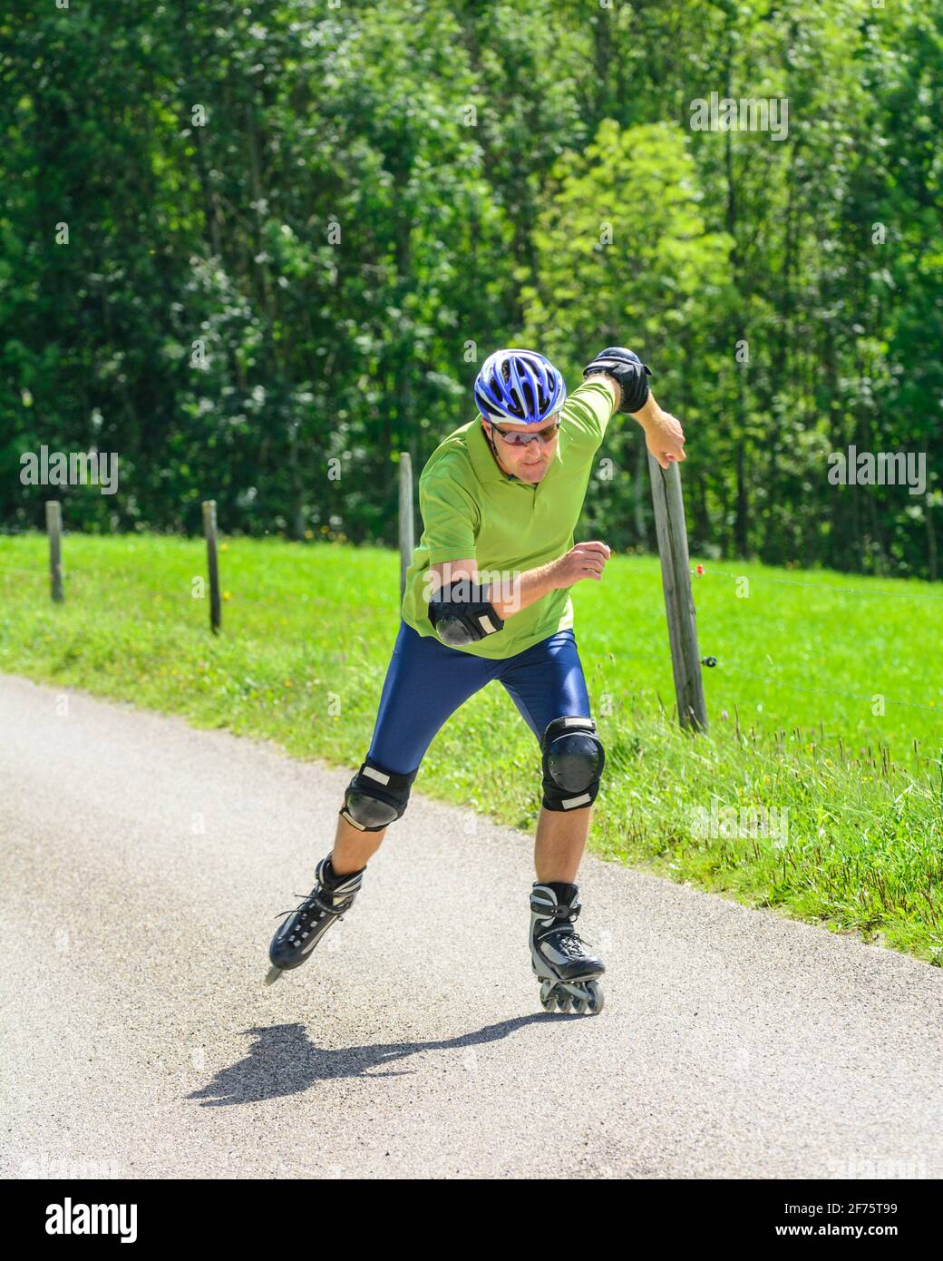 Hombre haciendo un tour de patinaje sobre patines en línea en el verde de  la naturaleza Fotografía de stock - Alamy