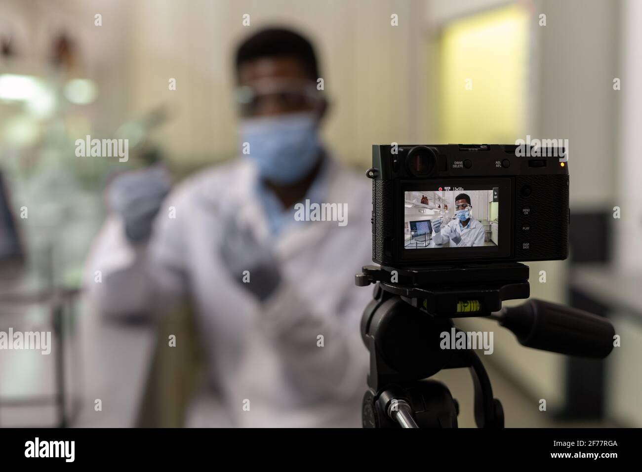 Joven científico africano sosteniendo tubo de ensayo con líquido y mirando  en la cámara que graba un vídeo para su blog Fotografía de stock - Alamy