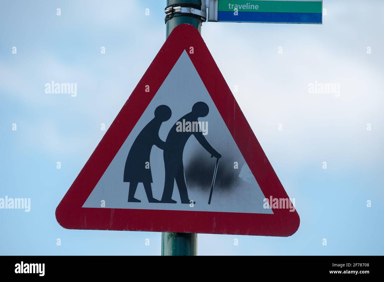 Personas mayores que cruzan la señal triangular de la carretera de advertencia. Foto de stock