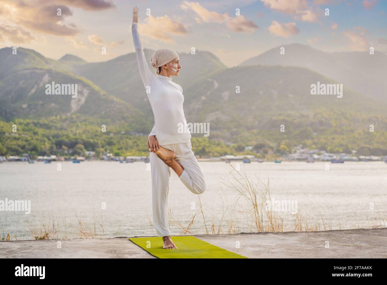 Kundalini yoga mujer con ropa blanca y turbante practica yoga kundalini en  el fondo del mar, las montañas y la puesta de sol. Lucha contra la pintura  de cara Fotografía de stock -