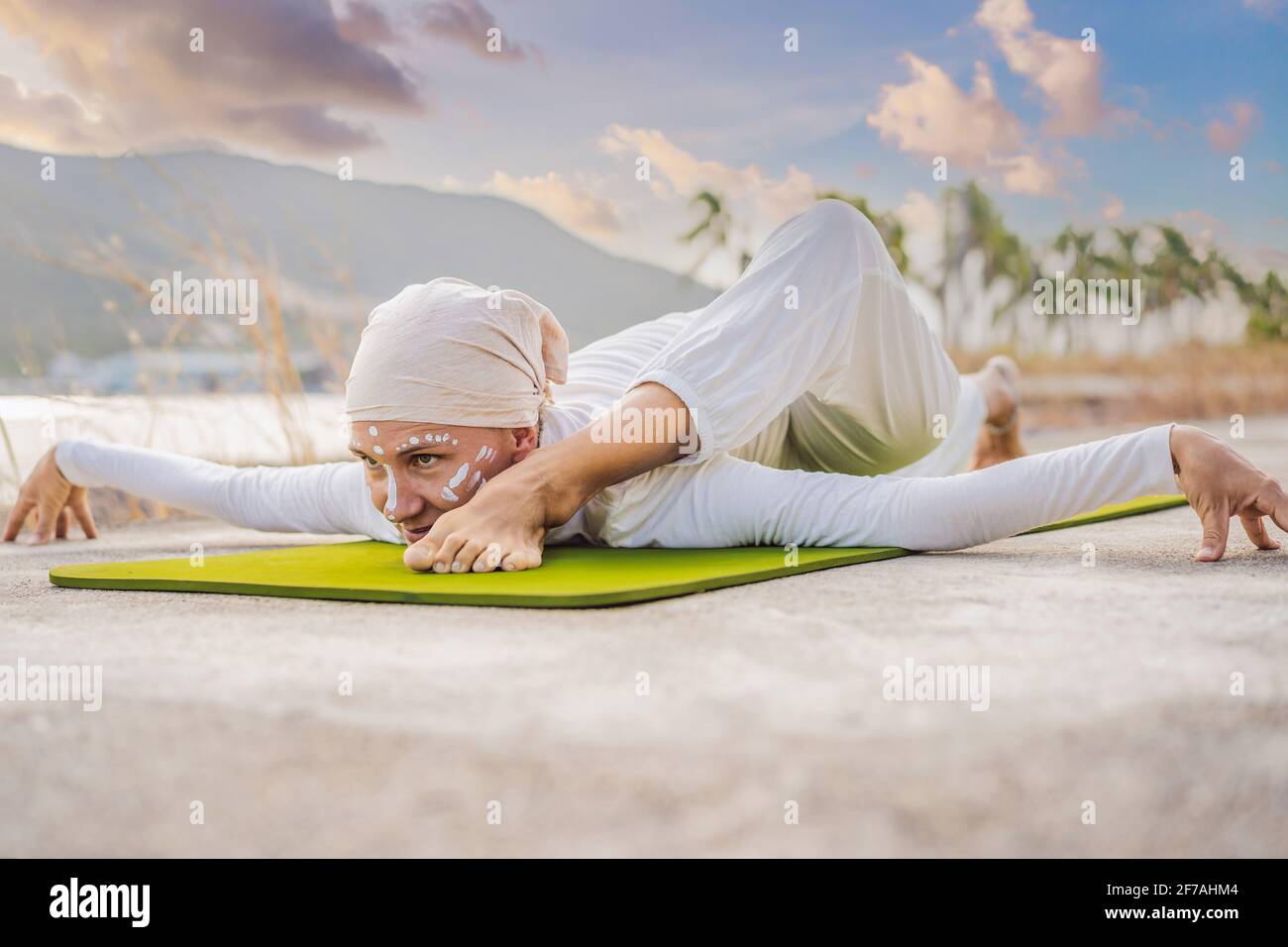 Kundalini yoga mujer con ropa blanca y turbante practica yoga kundalini en  el fondo del mar, las montañas y la puesta de sol. Lucha contra la pintura  de cara Fotografía de stock -