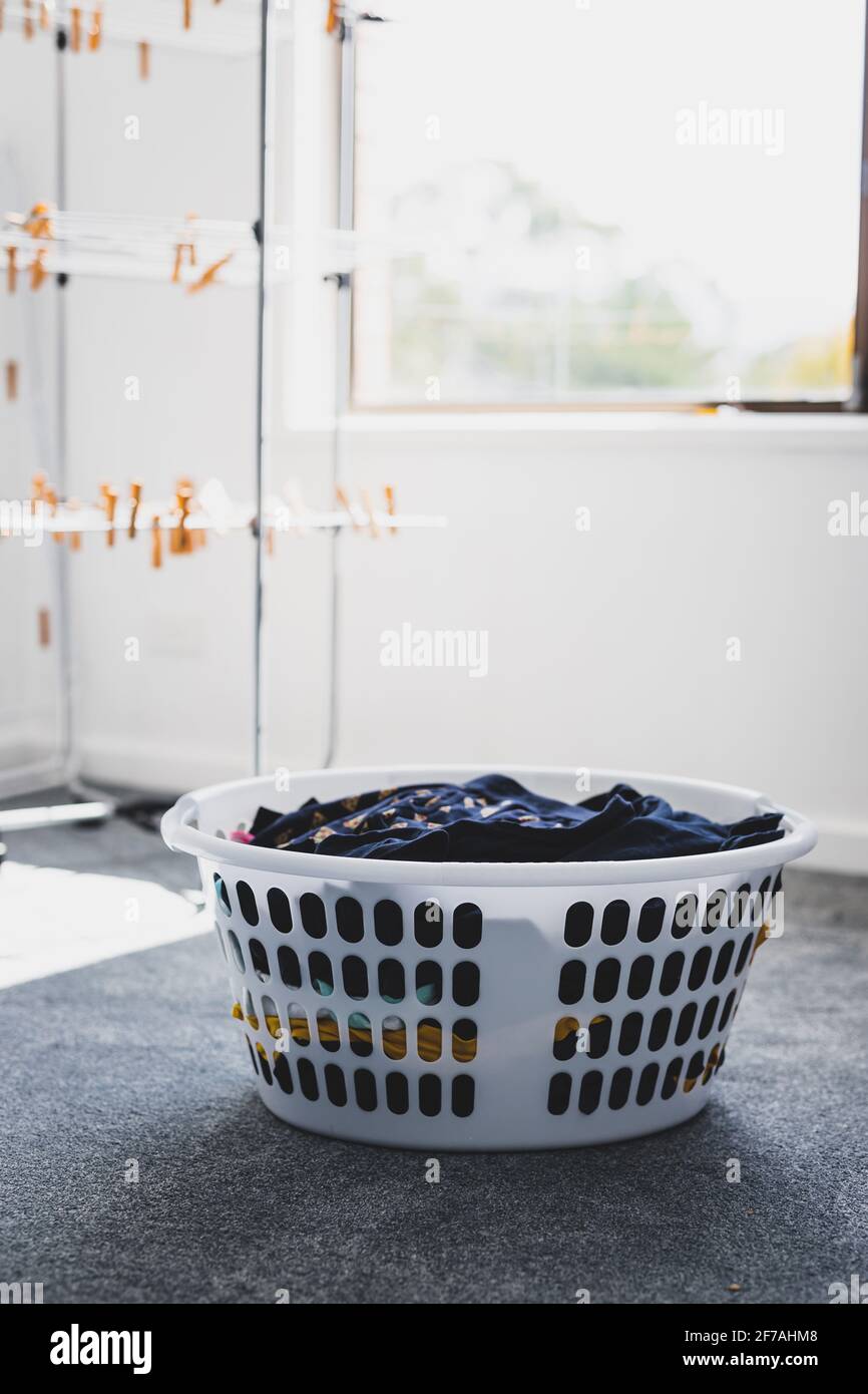 cesta de ropa con ropa limpia lista para colgar en el aire de la ropa junto  a ella, las tareas domésticas y el concepto de rutina de la vida diaria  Fotografía de