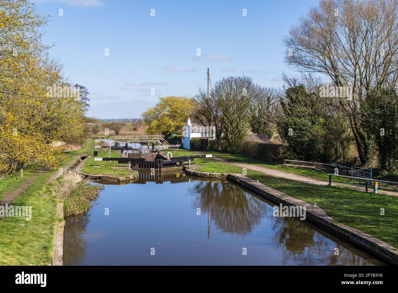 Una bonita casa blanca junto a una tranquila cerradura en la rama Rufford el Leeds Liverpool Canal cerca de Burscough, Lancashire en abril de 2021. Foto de stock