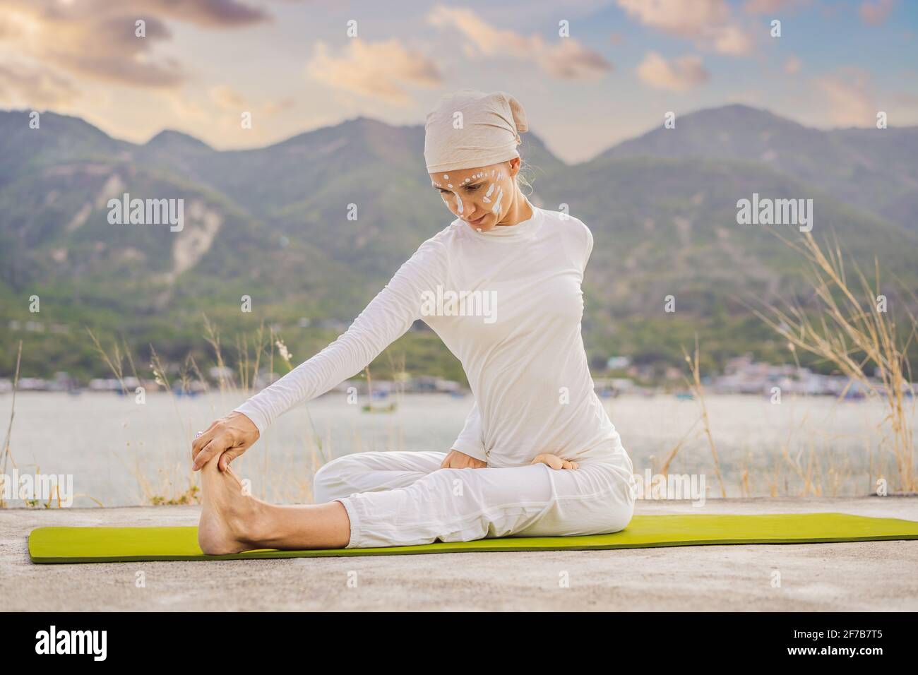 Kundalini yoga mujer con ropa blanca y turbante practica yoga kundalini en  el fondo del mar, las montañas y la puesta de sol. Lucha contra la pintura  de cara Fotografía de stock -