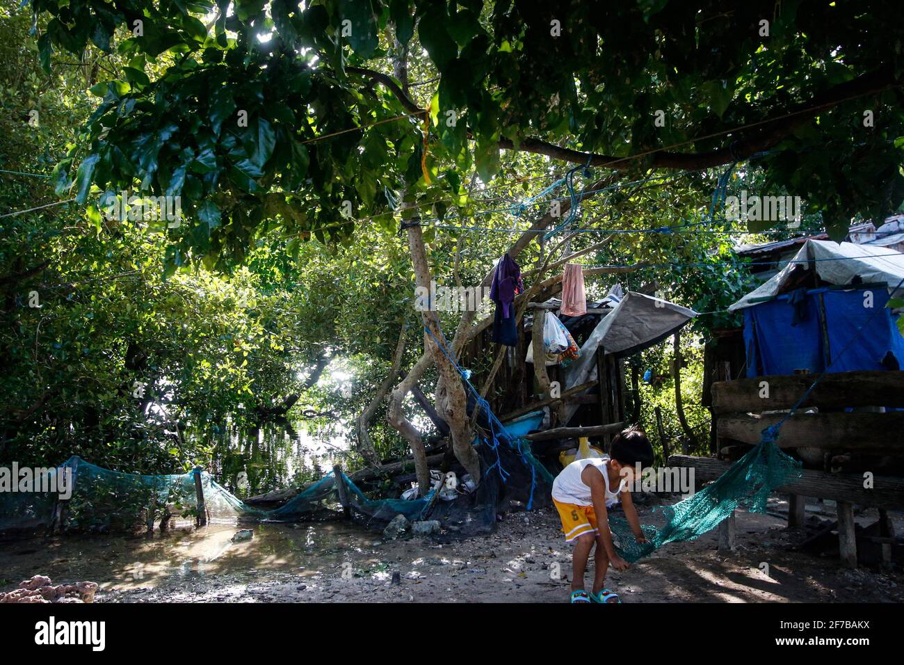 Un niño jugando en el patio trasero de su casa en Campuyong, Guyuan Samar Oriental. Este lugar está ahora amenazado por la subida del nivel del mar. Guiuan fue el sitio de primera caída durante el Super Typhoon Yolanda el 8 de noviembre de 2013 y considerado como una de las provincias vulnerables a los impactos del cambio climático. Filipinas. Foto de stock