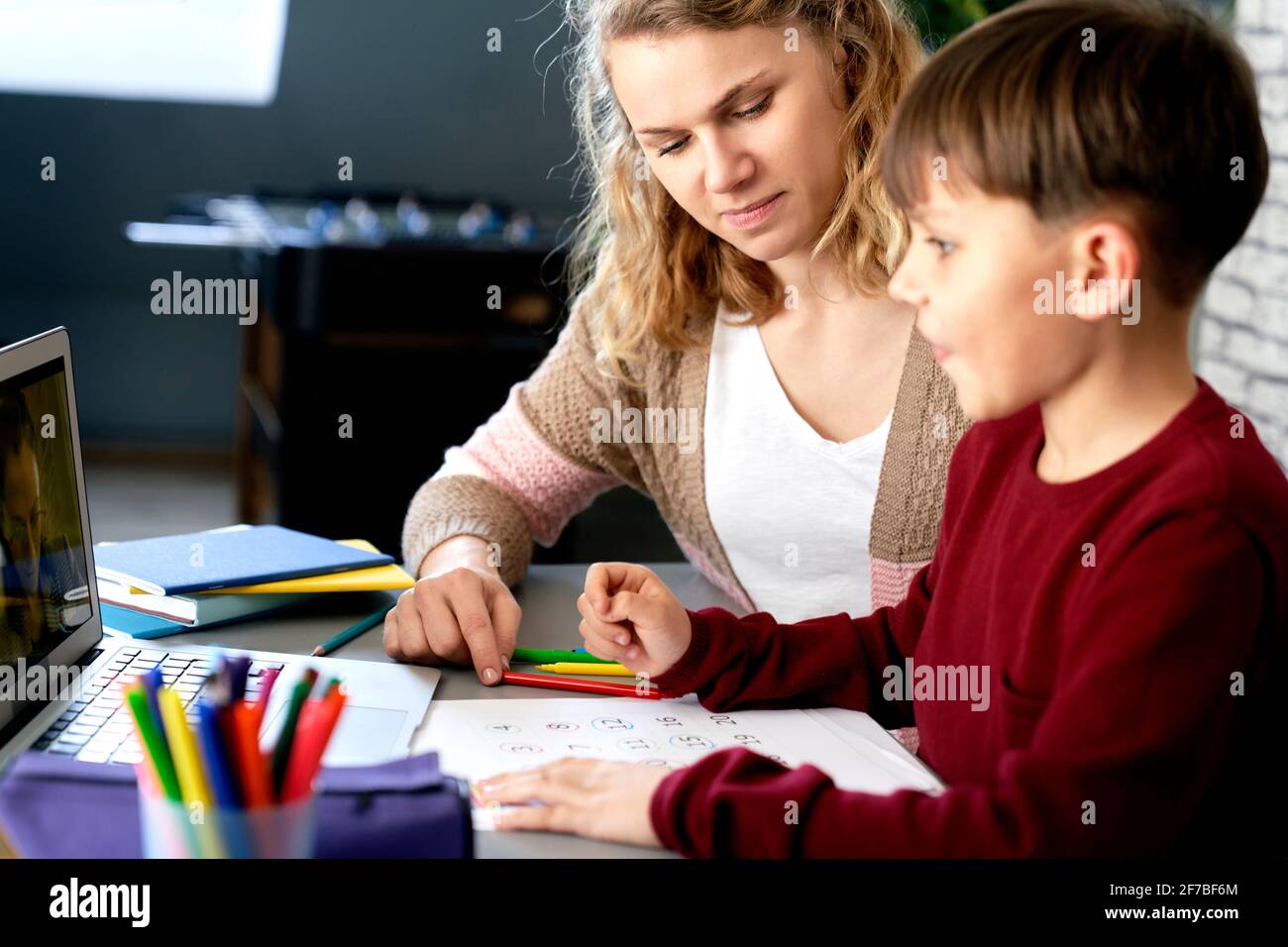 La madre ayuda a su hijo mientras estudia a distancia Foto de stock