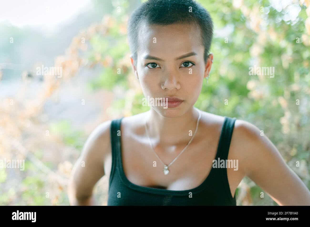 La cabeza de una joven mujer étnica asiática con pelo corto, usando un sujetador deportivo, mirando la cámara. Foto de stock