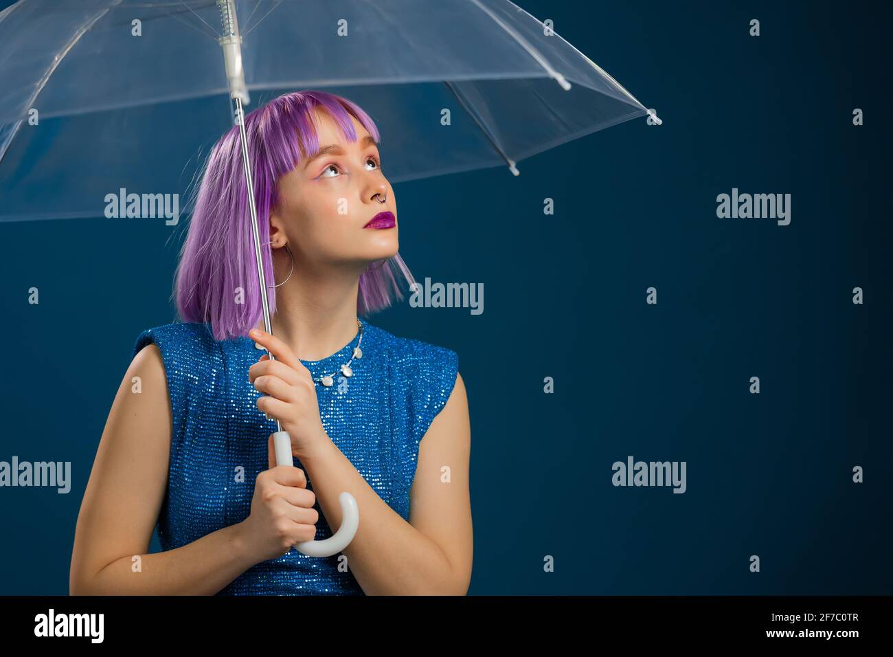 Inusual mujer de cabello violeta encuentra bajo el paraguas azul en el estudio. Concepto de chica moda, estilo de vida hipster, ropa de moda Fotografía de stock - Alamy