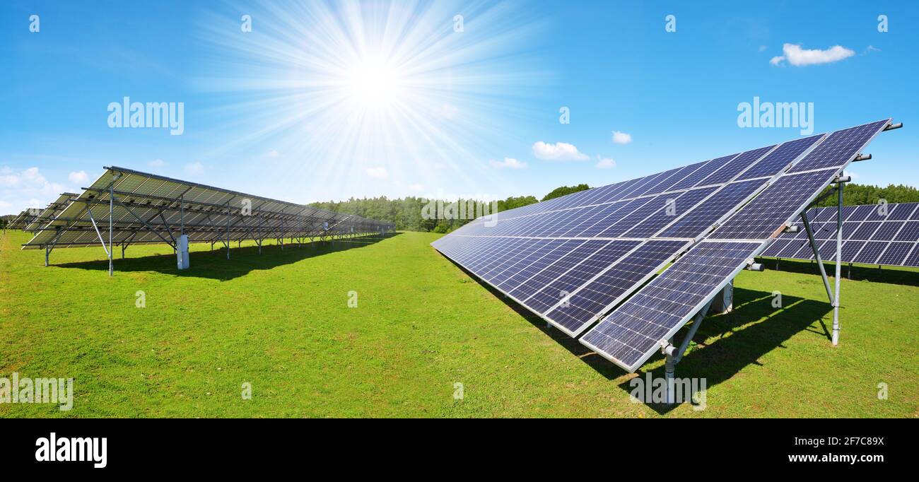 Paneles de energía solar en el prado con cielo soleado. Recursos sostenibles. Foto de stock