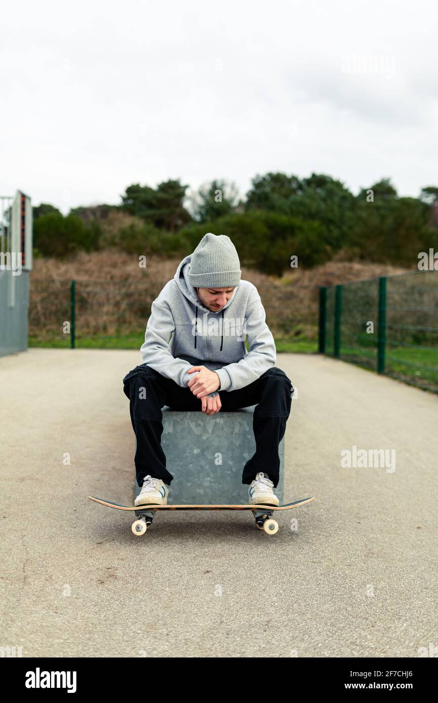 Retrato de un joven adulto con un monopatín sentado en una caja en un  parque local. Concepto de skateboard de estilo de vida saludable Fotografía  de stock - Alamy