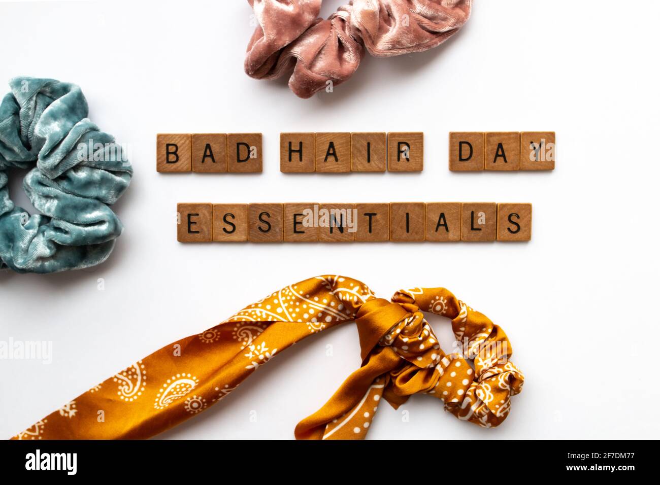 Las letras de madera deletrean 'lo esencial malo del día del pelo' en el centro de una tabla cubierta con el pelo de terciopelo y de seda scrunchies, Toronto, Ontario, Canadá. Foto de stock