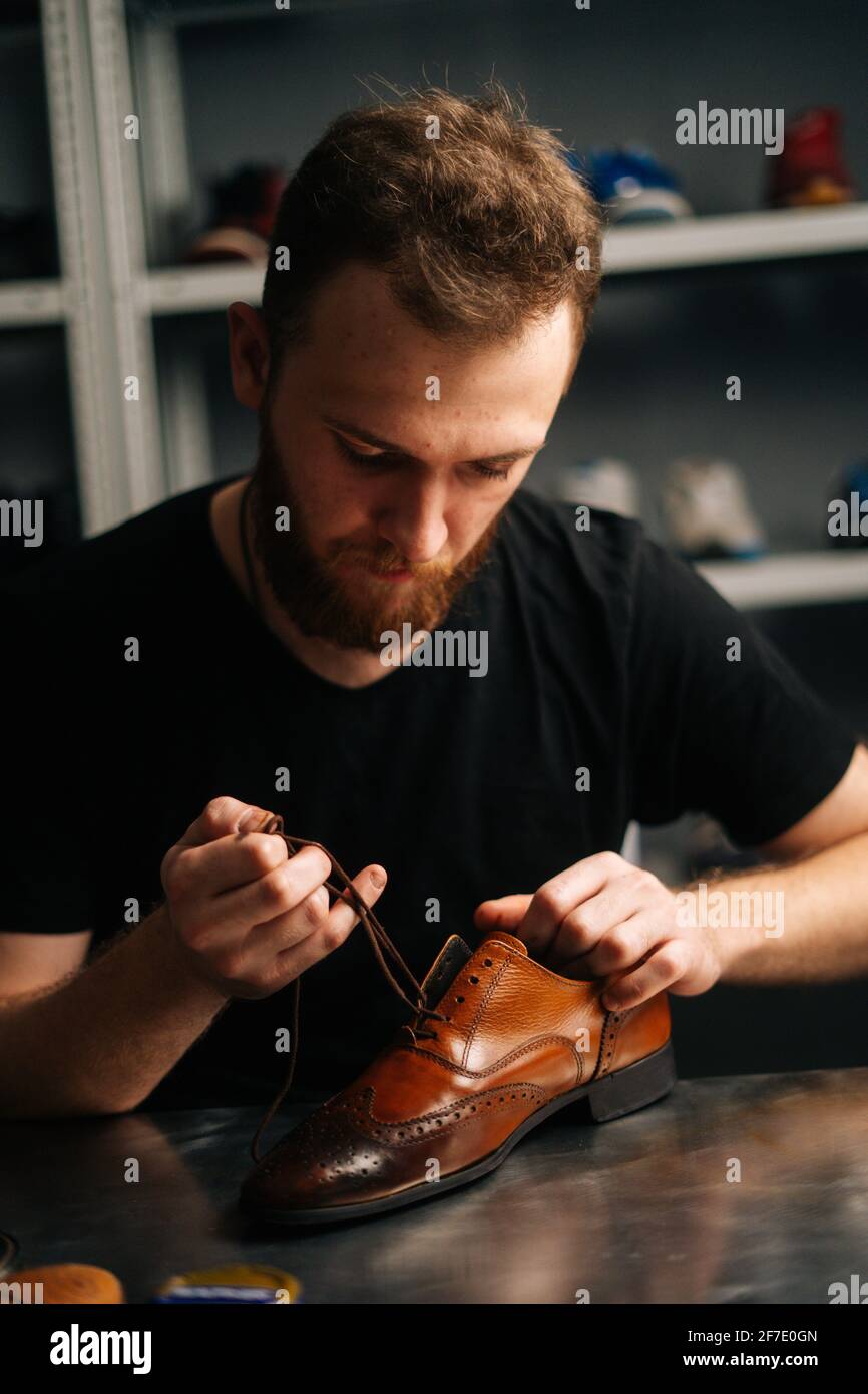 proteccion dominar Final Retrato de primer plano de zapatero macho que ata cordones en zapatos de  cuero marrón claro reparados y pulidos Fotografía de stock - Alamy