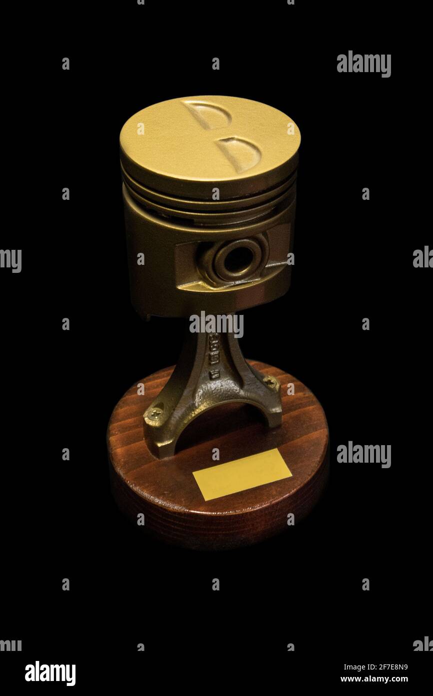 Un pistón dorado sobre una base de madera, utilizado como premio o copa