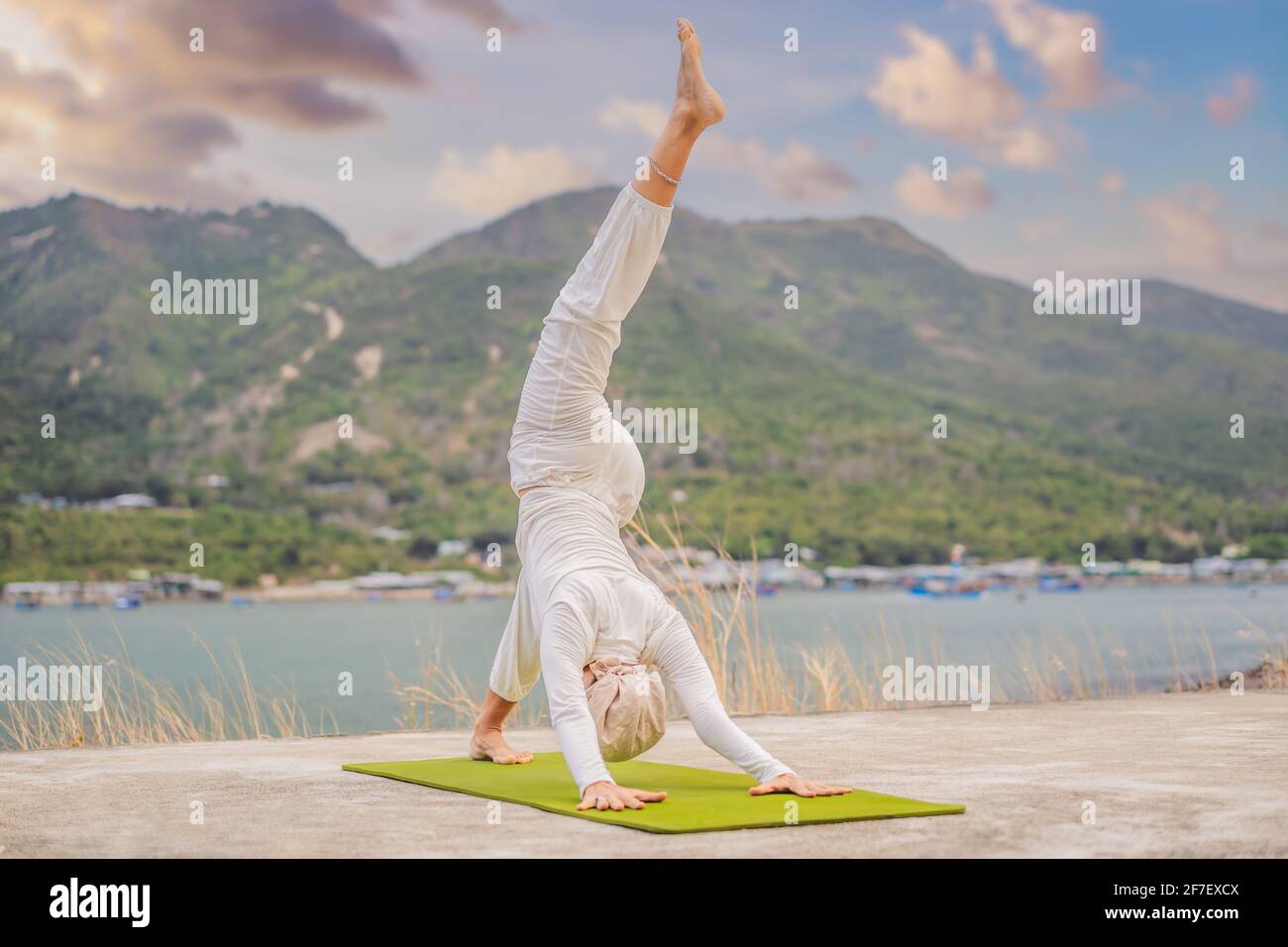 Kundalini yoga mujer con ropa blanca y turbante practica yoga kundalini en  el fondo del mar, las montañas y la puesta de sol. Lucha contra la pintura  de cara Fotografía de stock -