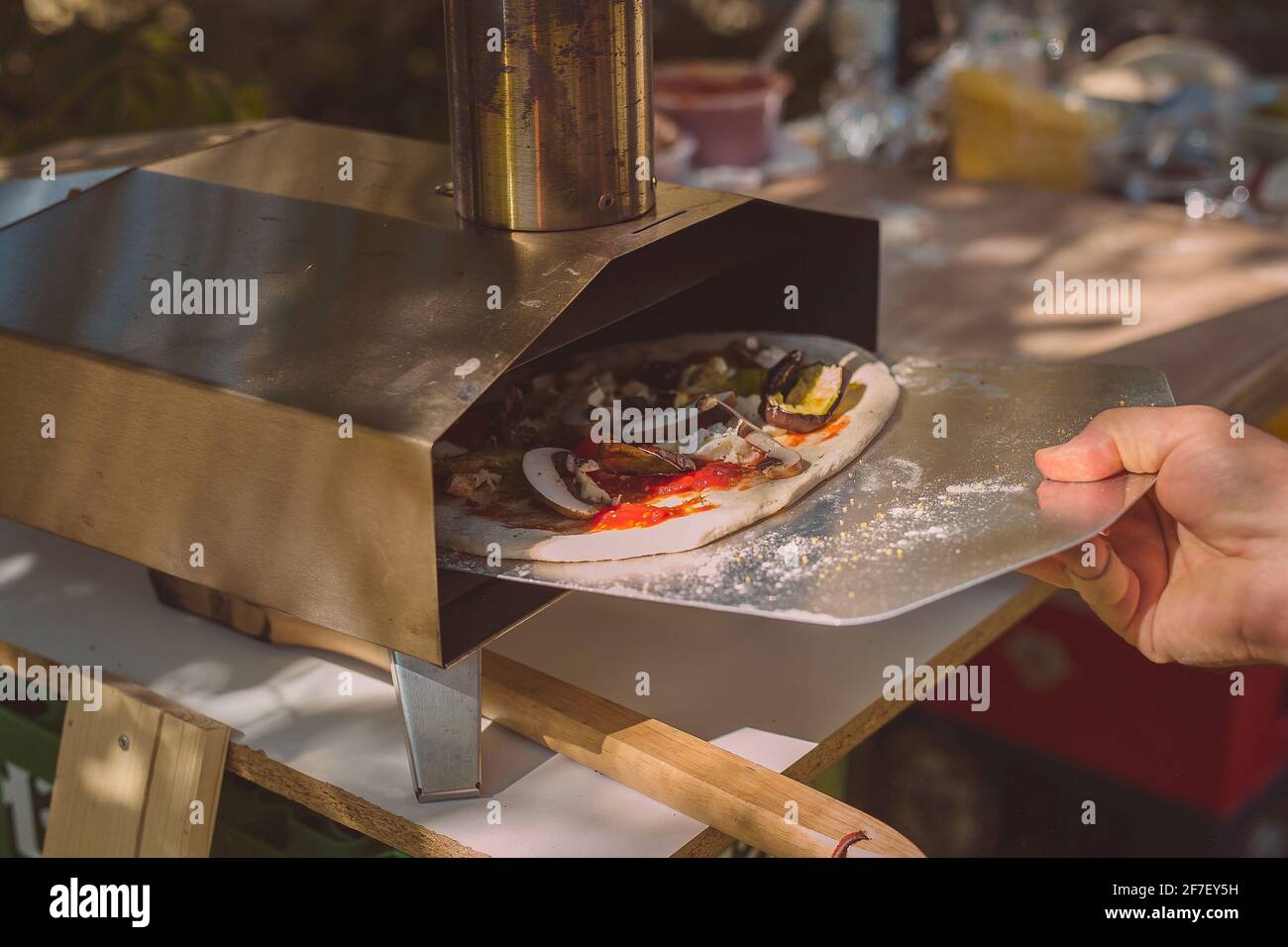 La pizza casera se prepara para ser insertada en un horno portátil de  aluminio para pizzas. Ingredientes visibles en el fondo Fotografía de stock  - Alamy