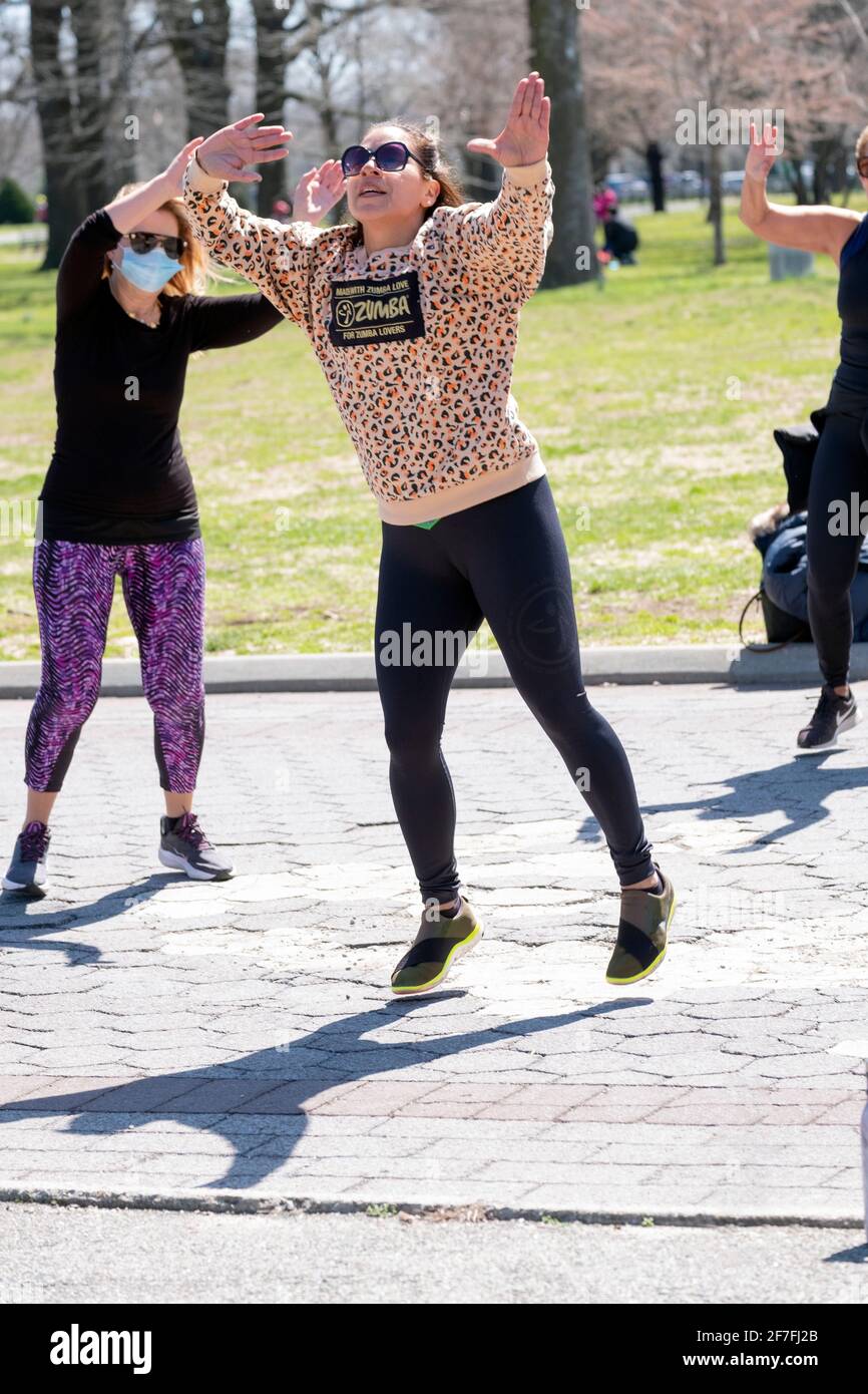 Una mujer dirige una clase de Zumba a través de un vigoroso ejercicio de baile en un parque en Queens, Nueva York. Foto de stock