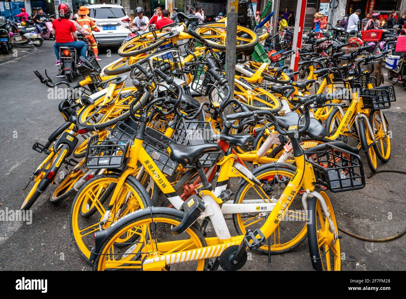 Haikou China , 21 de marzo de 2021 : Pila de bicicleta amarilla compartida de Meituan Alquiler de bicicletas en medio de una calle concurrida en Haikou Hainan China Foto de stock