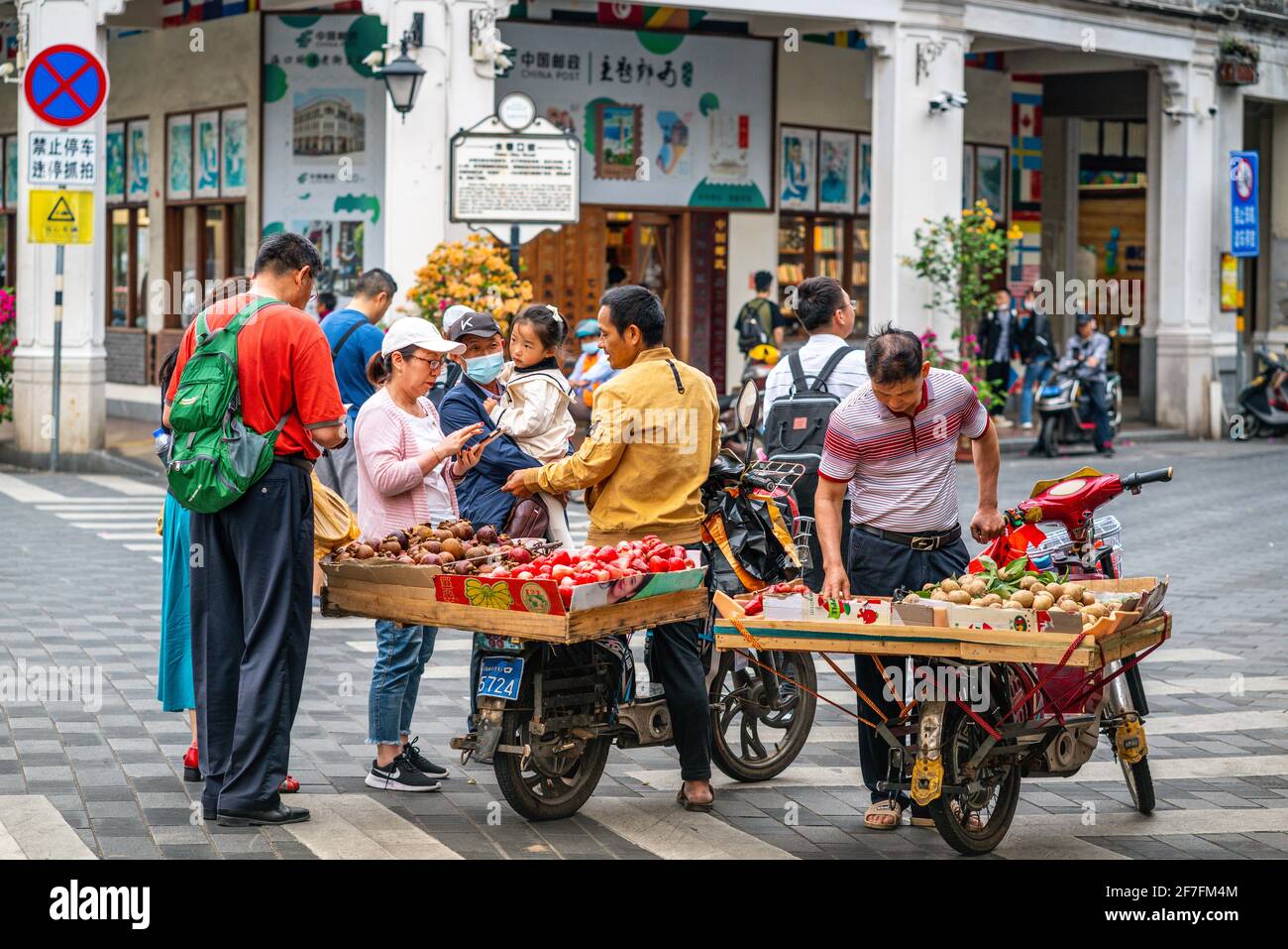 Haikou China , 21 de marzo de 2021 : Turistas chinos que compran frutas exóticas de pueblos locales que se encuentran en la calle del casco antiguo de Haikou, Hainan China Foto de stock
