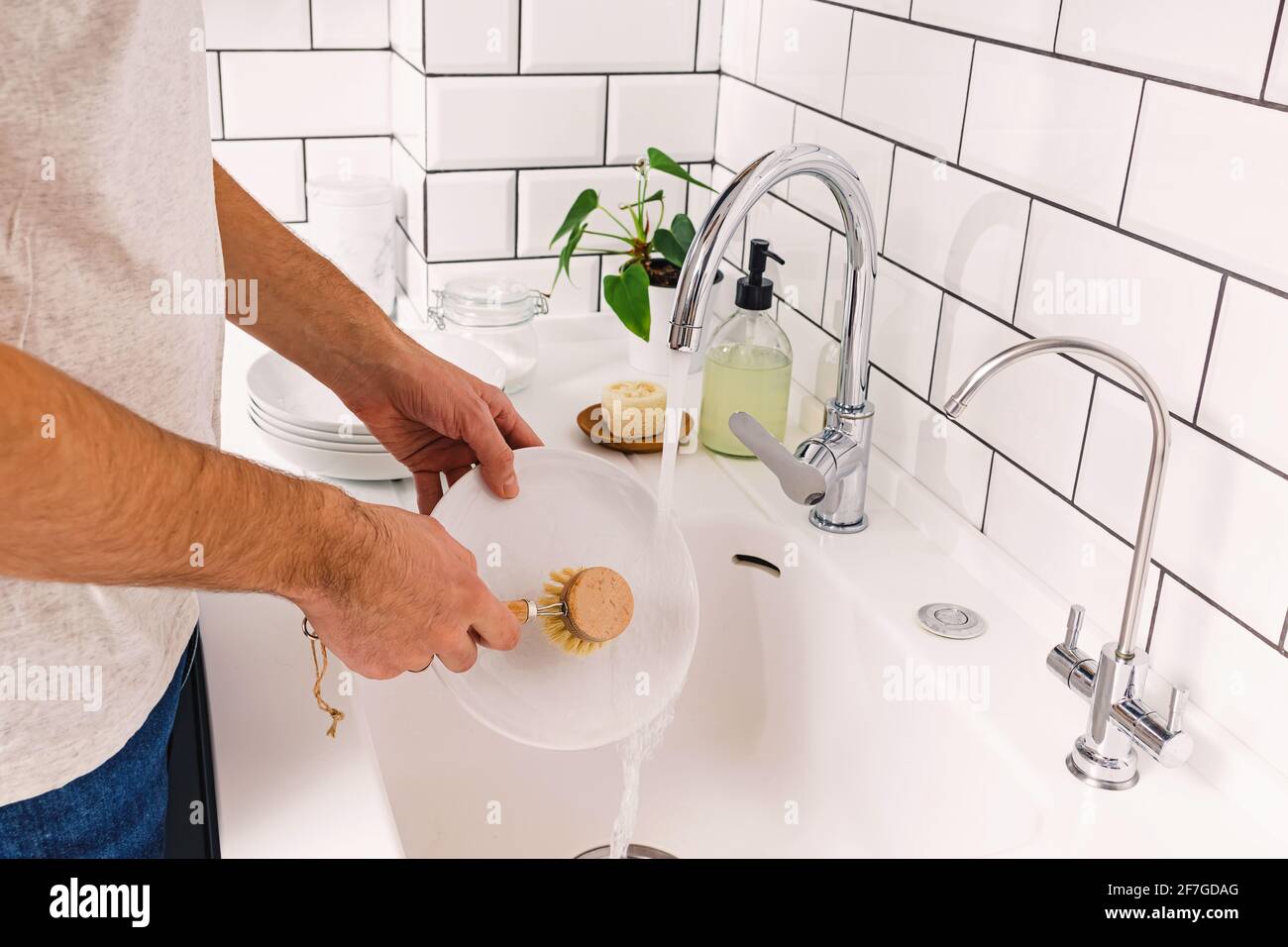 Un hombre lava platos en la cocina con madera cepillo ecológico Fotografía  de stock - Alamy