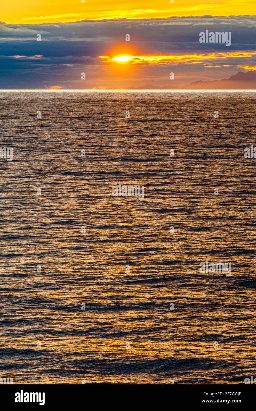 Una puesta de sol sobre la costa del Pacífico Noroeste, cerca de la Isla del Príncipe de Gales, Alaska, EE.UU. - Vista desde un crucero que navegaba el pasaje interior Foto de stock