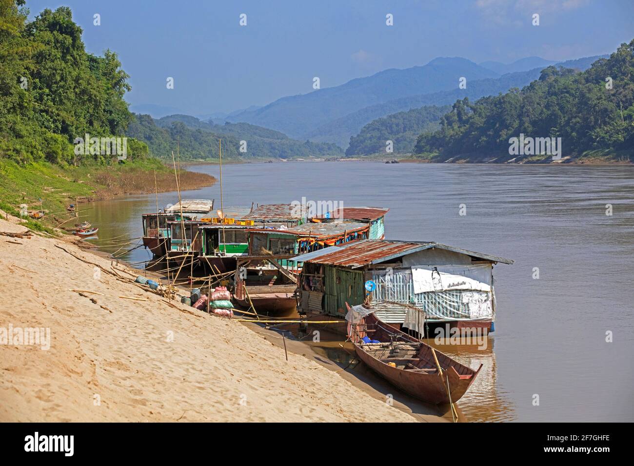 Slowboats / botes lentos para cruceros por el río a Luang Phabang / Luang Prabang / Louangphabang en el río Mekong al atardecer, Laos Foto de stock