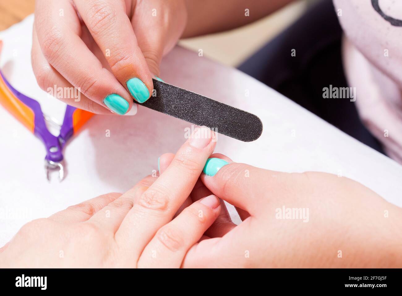 Closeup shot de una mujer en un salón de uñas reciben una manicura por una esteticista con lima de uñas. Mujer obteniendo Uña Manicura. Esteticista uñas de archivo a C Foto de stock