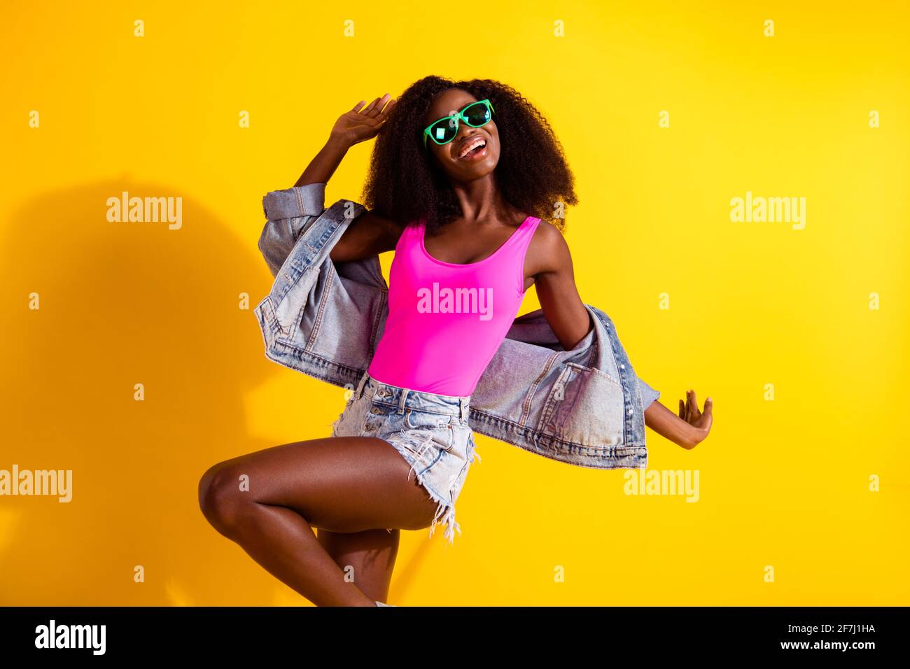 Foto de encantadora hermosa mujer afro americana joven usar gafas pantalón  corto denim baile aislado sobre fondo de color amarillo Fotografía de stock  - Alamy