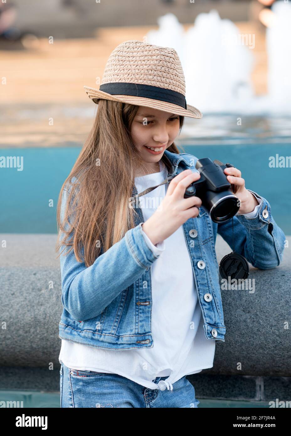 Chica abrigo vaquero, sombrero de paja y jeans con cámara caminando por el centro de la ciudad y haciendo fotos Fotografía de stock Alamy
