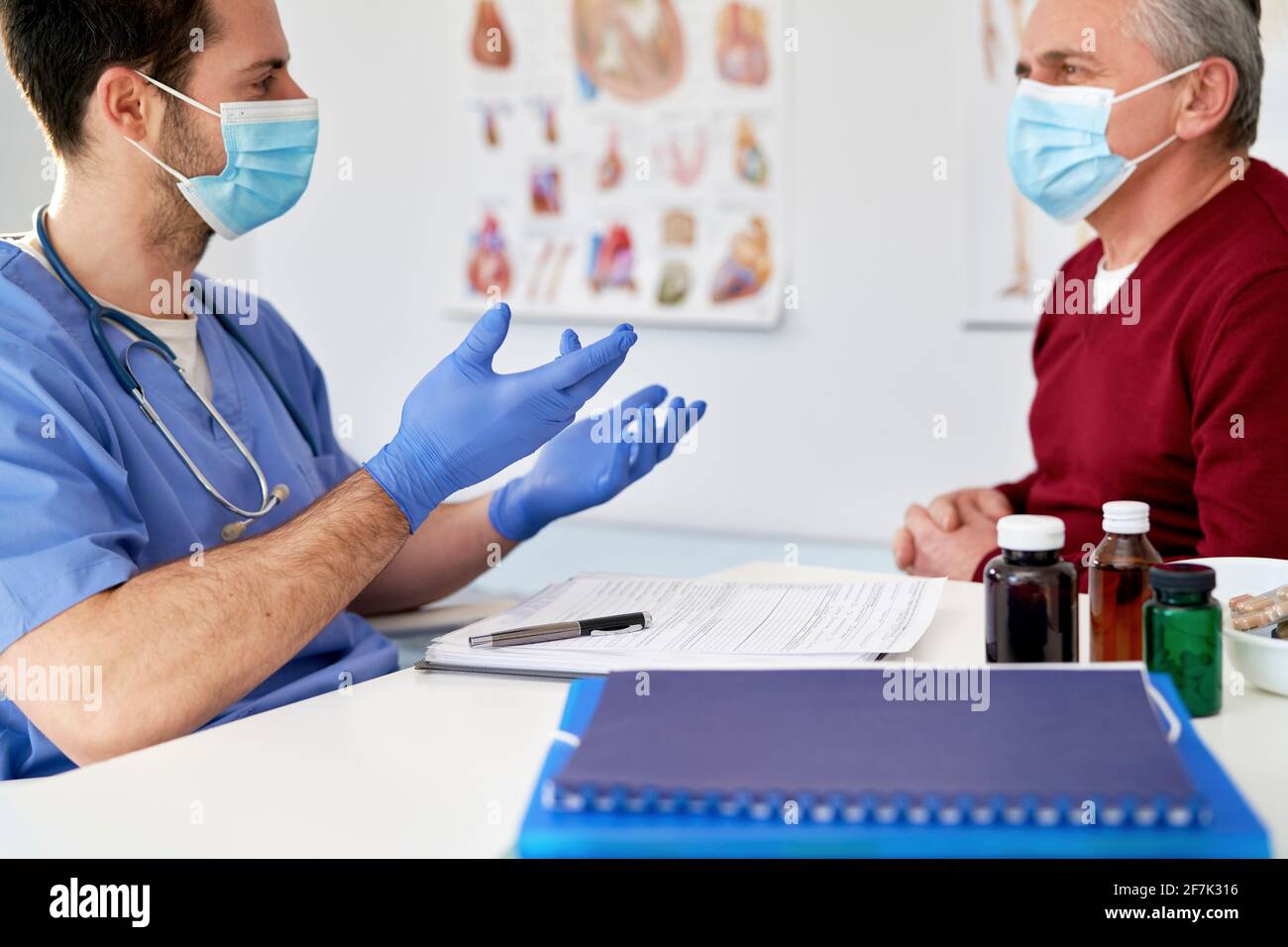 Doctor en máscara protectora hablando con un paciente mayor Foto de stock