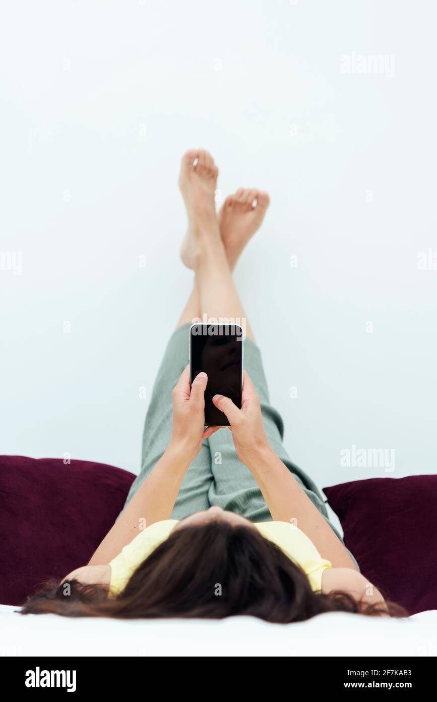 Mujer acostada en cama comprobando sus redes sociales. Concepto de estilos de vida. Foto de stock