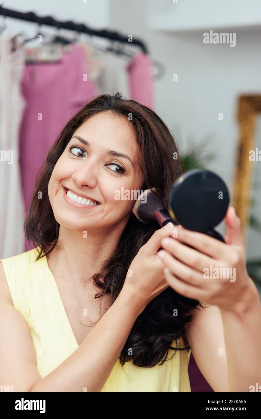 Joven chica latina maquillarse frente al espejo de aplicar la base de  maquillaje con una brocha Fotografía de stock - Alamy