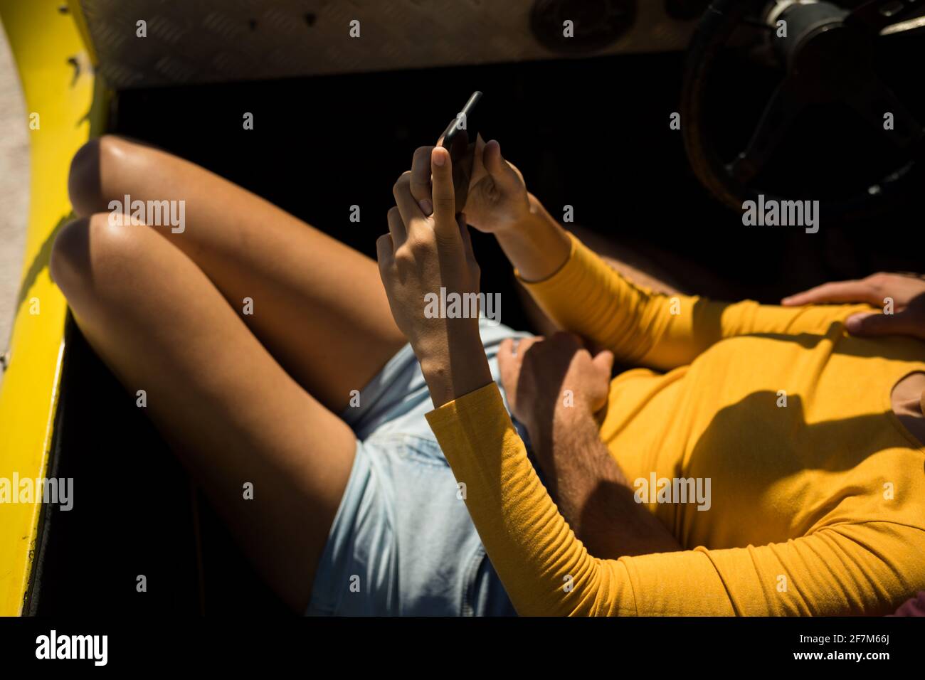 Sección media de mujer caucásica tumbada en un cochecito de playa junto al mar con smartphone Foto de stock