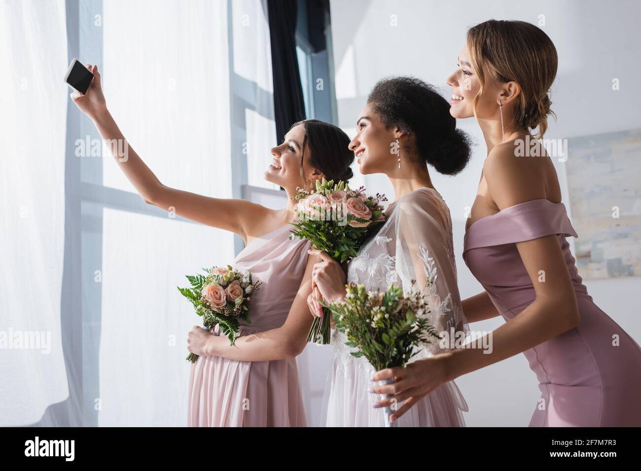 novia afroamericana con novias celebrando ramos de boda mientras tomaba selfie en el smartphone Foto de stock