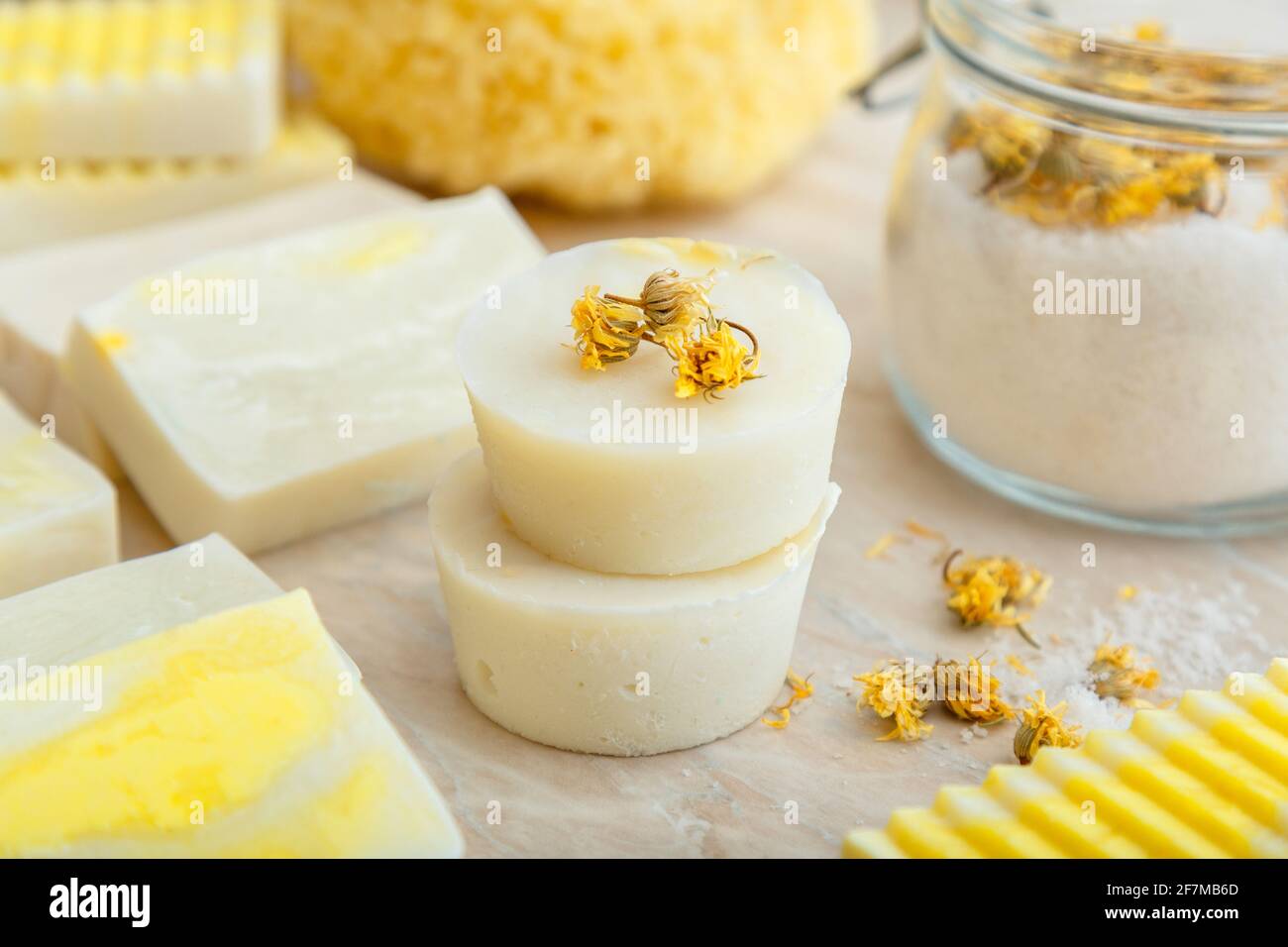 Barras redondas de jabón blanco con hierbas secas flores de marigold.  Productos de baño de spa sal aromática, muchos jabones artesanales  naturales sobre mesa de mármol. Sólido champú bar Fotografía de stock -